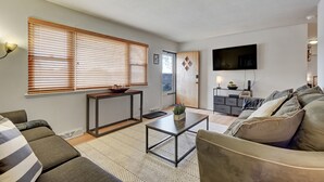 A modern living room with a sofa, a coffee table, and a TV mounted on the wall.