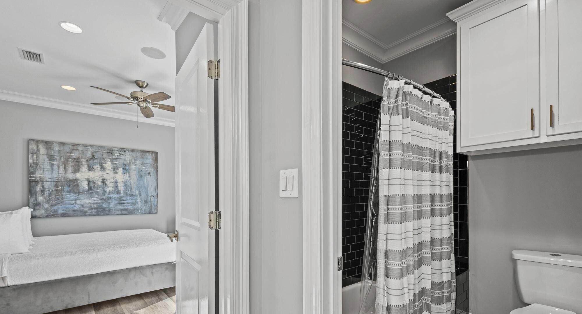 A bathroom with a shower curtain, a toilet, and a ceiling fan.