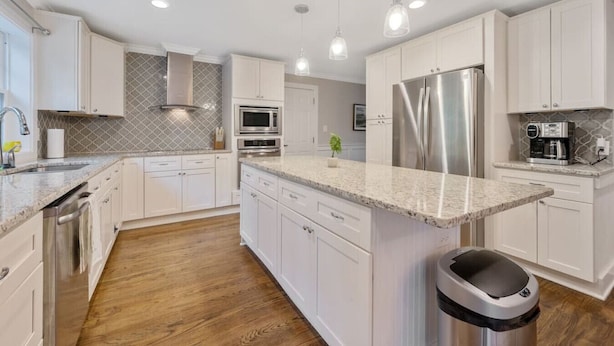 A modern kitchen with white cabinets, stainless steel appliances, and a granite countertop. - Ping-pong | 10-min to NC State | Fire Pit | BBQ (Raleigh)