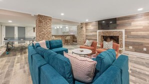 A modern living room with a sectional sofa, a coffee table, and a fireplace. - Ping-pong | 10-min to NC State | Fire Pit | BBQ (Raleigh)