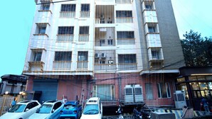 A multi-story building with balconies, parked cars, and motorcycles in front. - Blossoms Hotel and Service Apartment (Chennai)