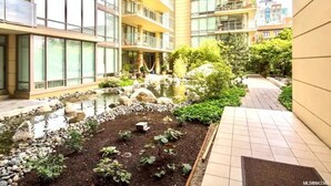 A courtyard with a small pond, surrounded by a building with multiple balconies and large windows. - Waterfalls Hotel in Downtown With Stunning Views! (Victoria)