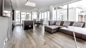 A modern living room with a sectional sofa, a dining table, and a kitchen area. - Waterfalls Hotel in Downtown With Stunning Views! (Victoria)
