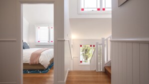 A bedroom with a bed, a window with blinds, a staircase, and a view of greenery outside. - Seaside apartment, 100m to beach (Narrabeen)