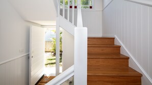 A staircase with wooden steps and white railings leading to an open doorway. - Seaside apartment, 100m to beach (Narrabeen)