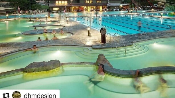 Um spa com várias piscinas e um toboágua, cercado por montanhas.