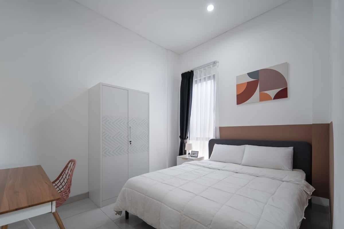 Ein Schlafzimmer mit einem Bett, einem Kleiderschrank, einem Schreibtisch und einem Stuhl.