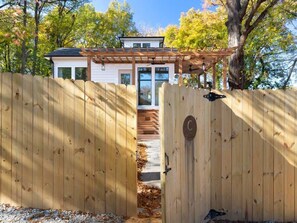 A wooden gate leading to a house with a covered porch and a visible deck. - Designer Garden Home Downtown (Durham)