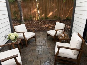 A patio area with four wooden chairs and a table, surrounded by a wooden fence and a tree. - Designer Garden Home Downtown (Durham)