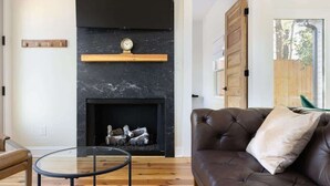 Una sala moderna con chimenea, sofá de cuero y una mesa de centro de vidrio.