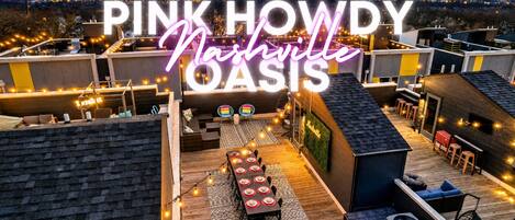 Rooftop lounge with dining table, string lights, and city views becomes the natural gathering spot for your group to take in the evening before heading out