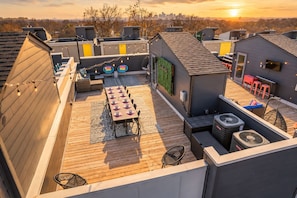 A rooftop terrace with a dining table set, outdoor seating, and a view of the city skyline. - Nashville-themed house sleeps 12 with ping pong & garage wall near Broadway (Nashville)