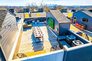 A rooftop terrace with a wooden deck, a dining table with chairs, and a small seating area with a table and chairs.