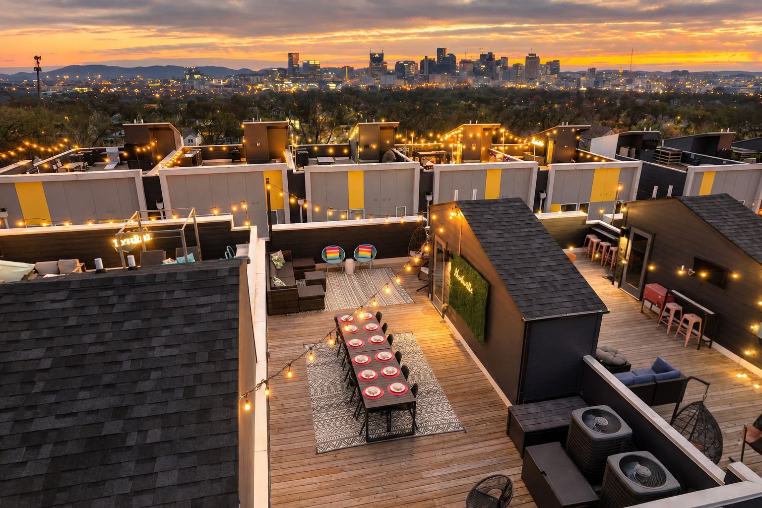 A rooftop terrace with a dining area, seating, and a view of the city skyline at sunset.