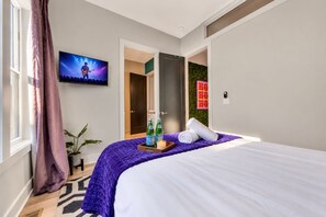 A hotel room with a bed, a television, a door leading to another room, and a wall with a holiday decoration. - Fall getaway: Nashville-themed house, sleeps 12, ping pong, 4 baths (Nashville)