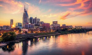 A city skyline at sunset with a river in the foreground.