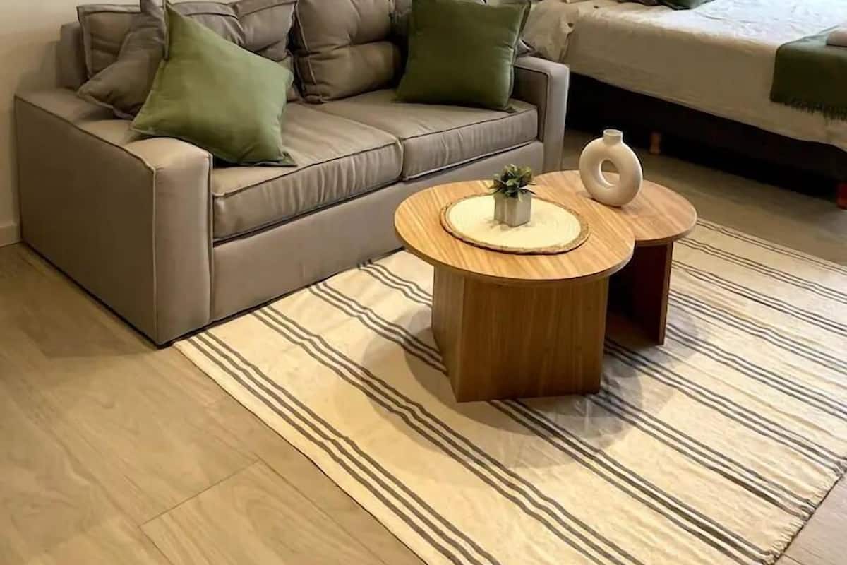 A modern living room with a sofa, two side tables, and a bed with a view.