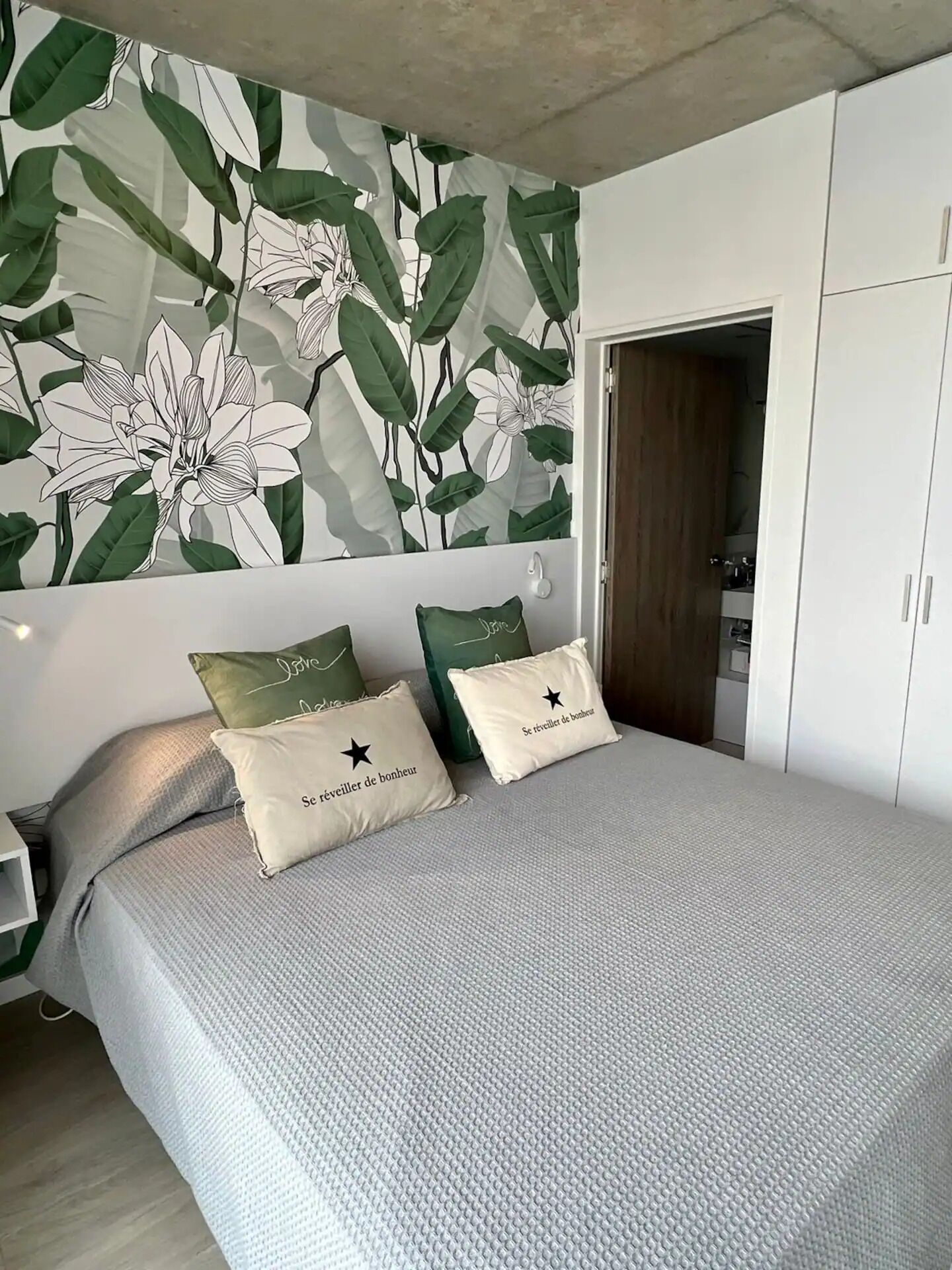 A bedroom with a large bed, a wardrobe, and a door leading to a bathroom.
