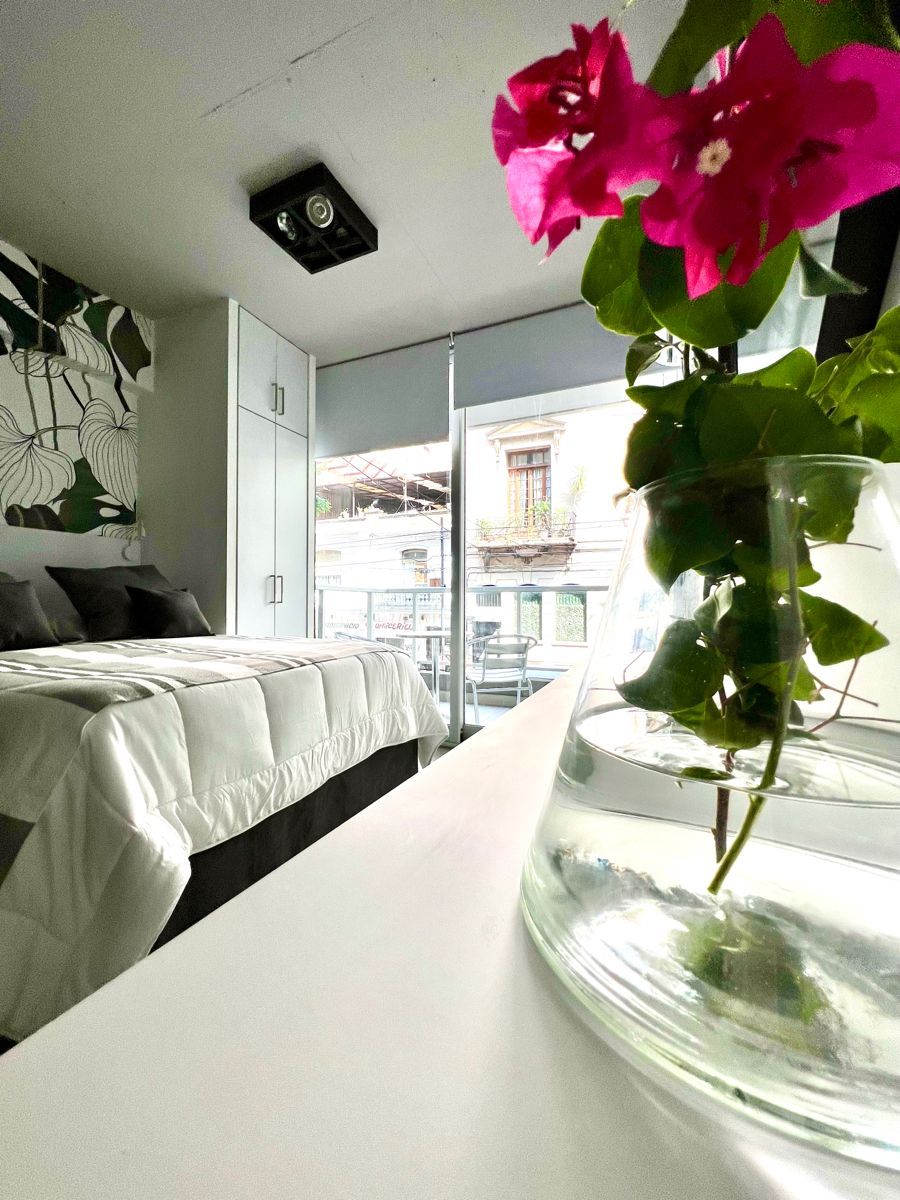 Ein Hotelzimmer mit einem Bett, einem weißen Tisch und einer Vase mit Blumen.