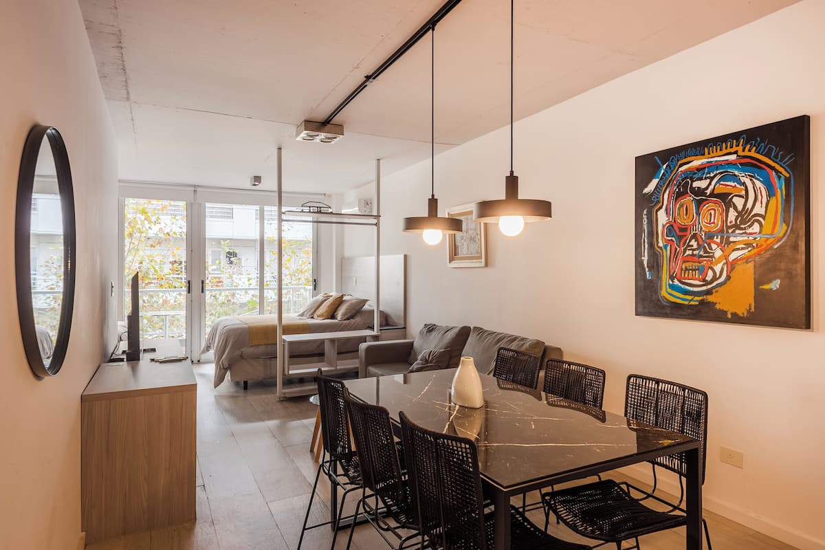 A modern interior with a dining area, a sofa, and a large abstract painting on the wall.