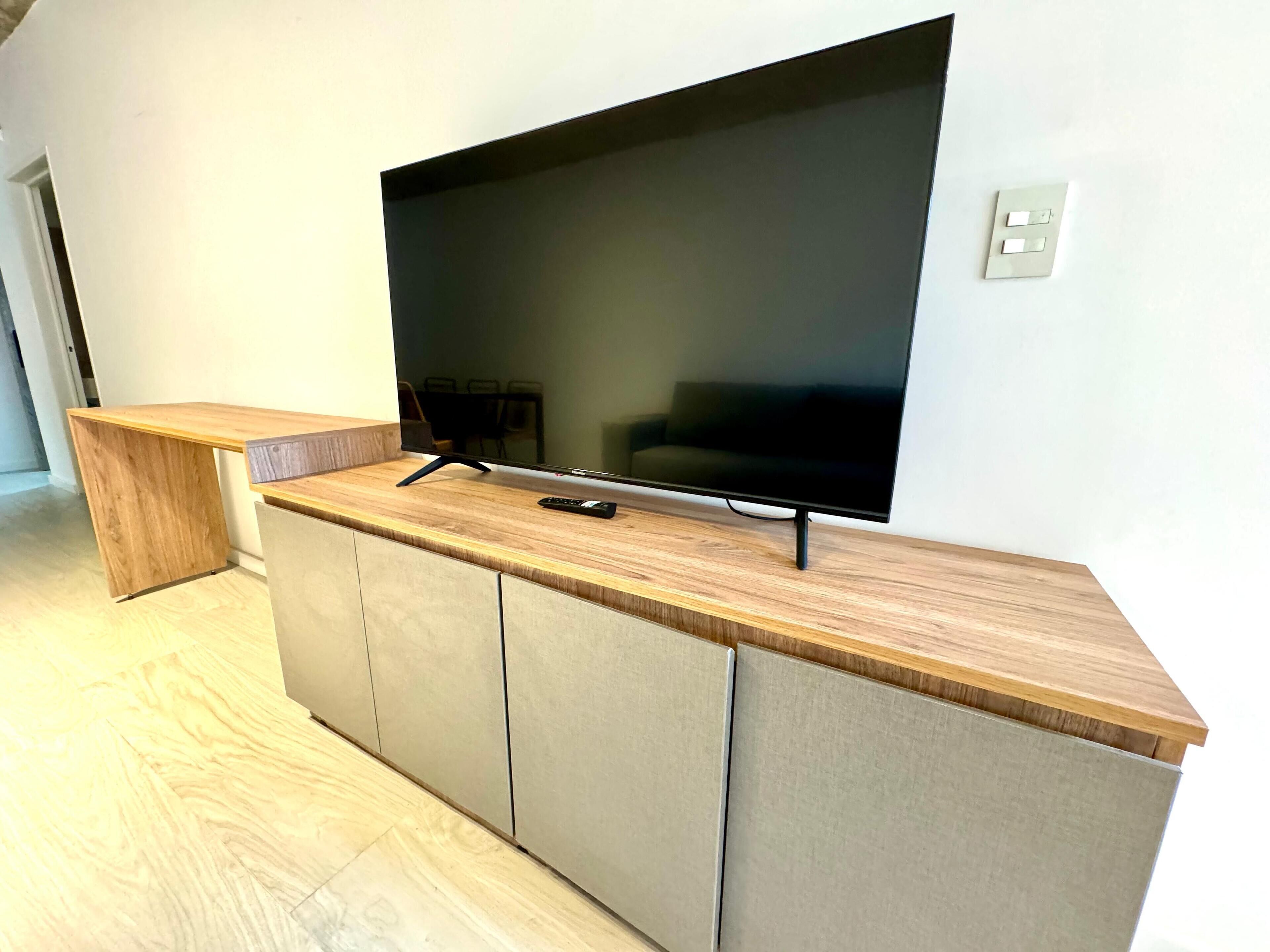 A modern living room with a large flat-screen TV mounted on a wooden console table.