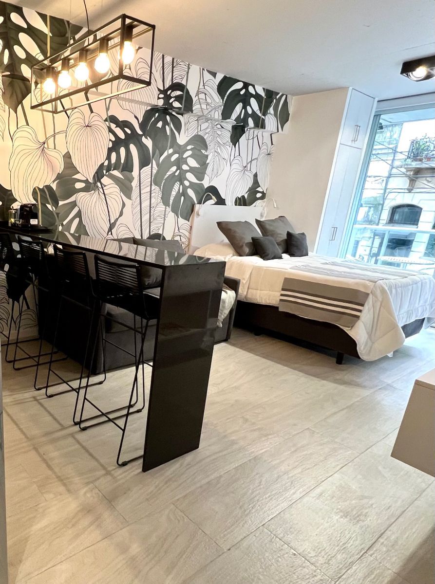 Ein modernes Schlafzimmer mit einem Bett, einem Schreibtisch mit Stühlen und einem großen Fenster.