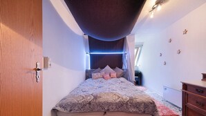 A bedroom with a bed, a wooden door, a dresser, and a ceiling with a starry design. - Holiday Apartment 'Mole Valley Ranch 2' with Balcony and Wi-Fi (Elmlohe)