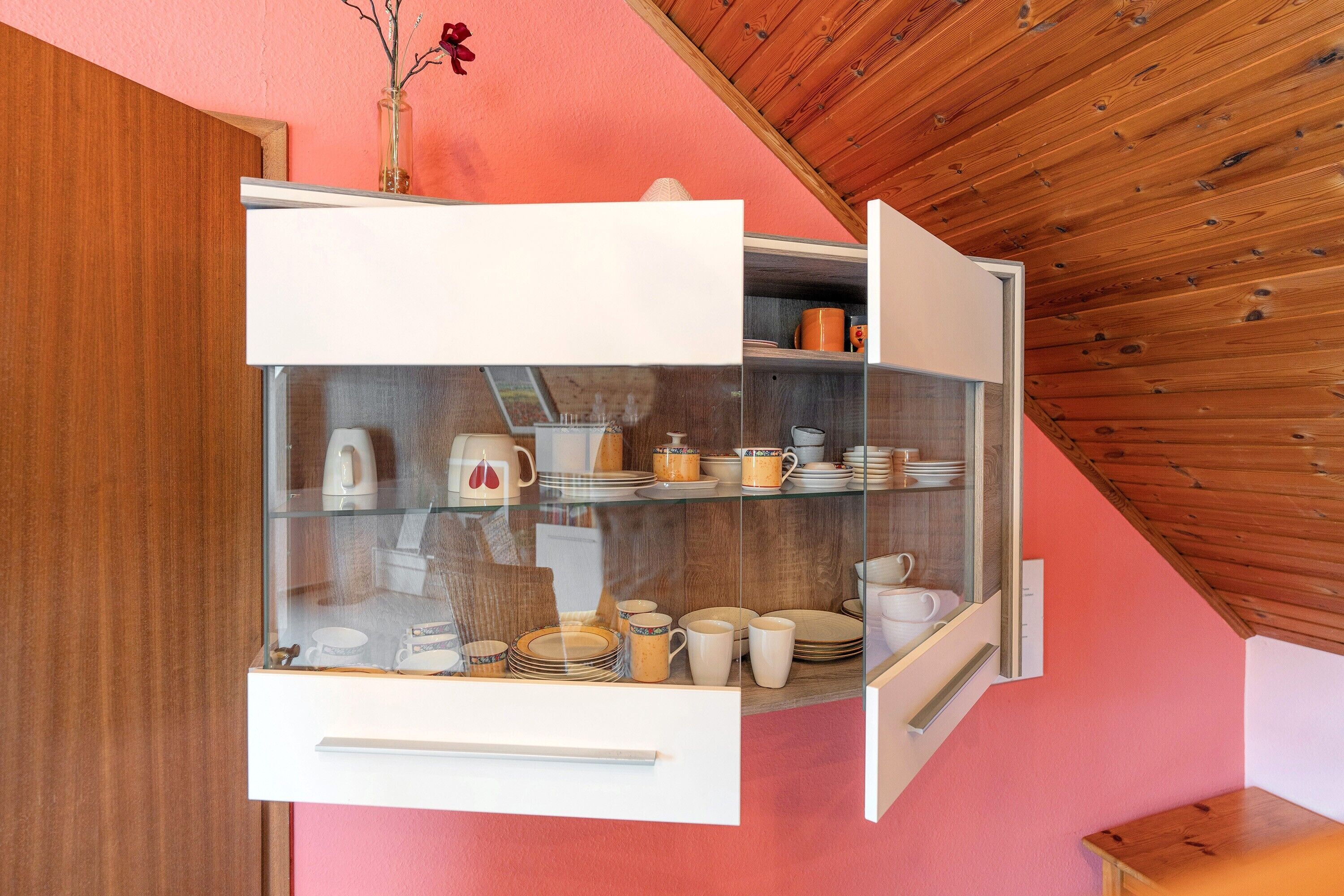 A kitchen with a glass-fronted cabinet displaying dishes and a coffee maker.