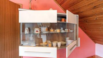 A kitchen with a glass-fronted cabinet displaying dishes and a coffee maker.