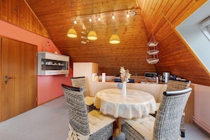A cozy dining area with wicker chairs, a round table, and pendant lights.