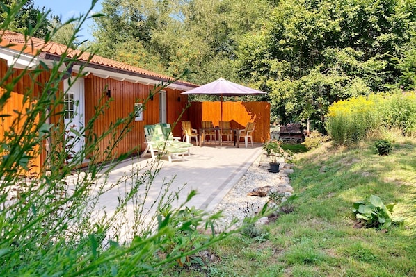 Une cabane en bois dotée d’une terrasse, d’un espace salon extérieur et d’un jardin.