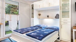 A bedroom with two beds, a wardrobe, and a glass cabinet.