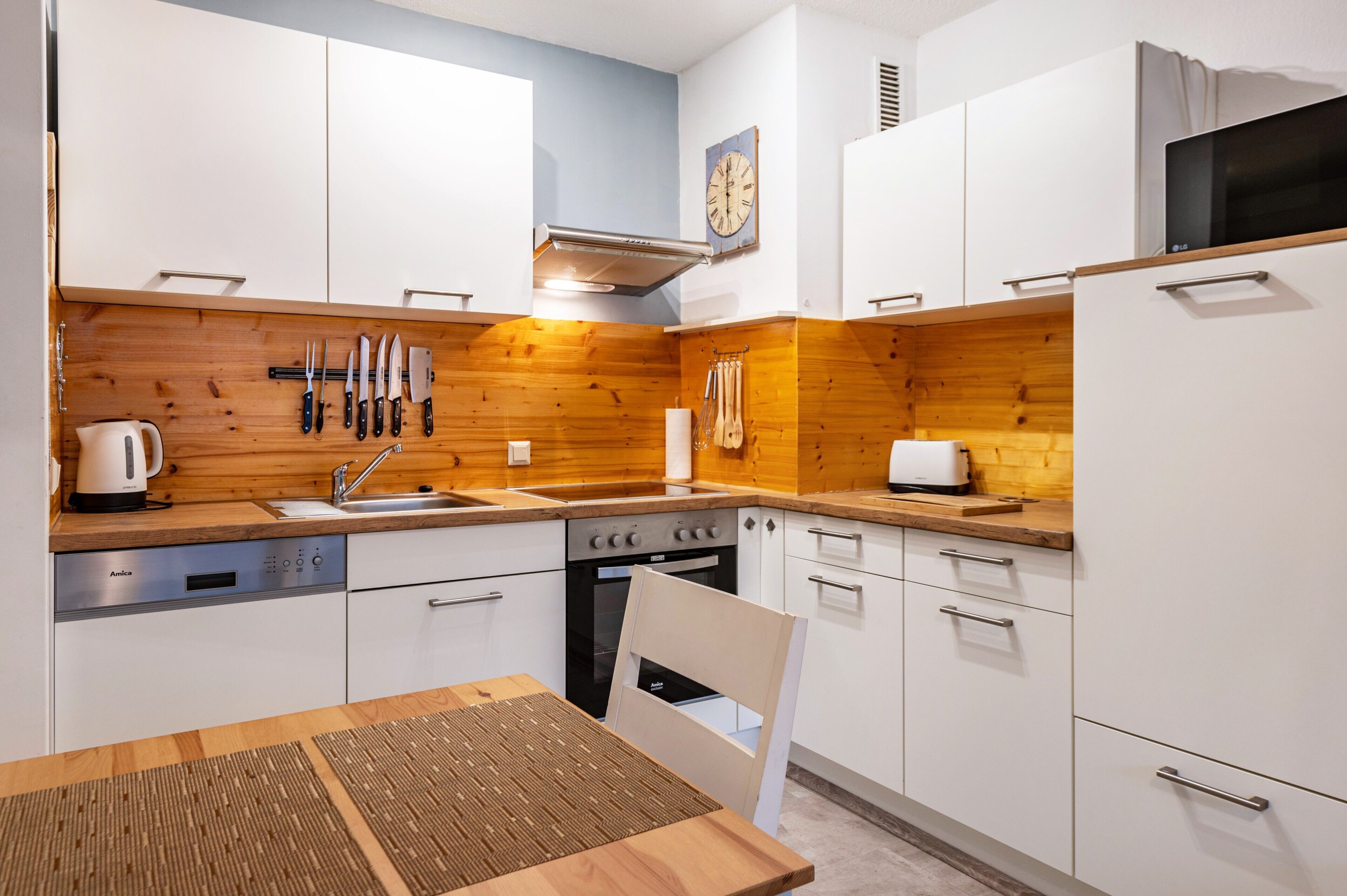 Eine moderne Küche mit weißen Schränken, Holzarbeitsplatten, einem eingebauten Backofen und einer Kaffeemaschine.