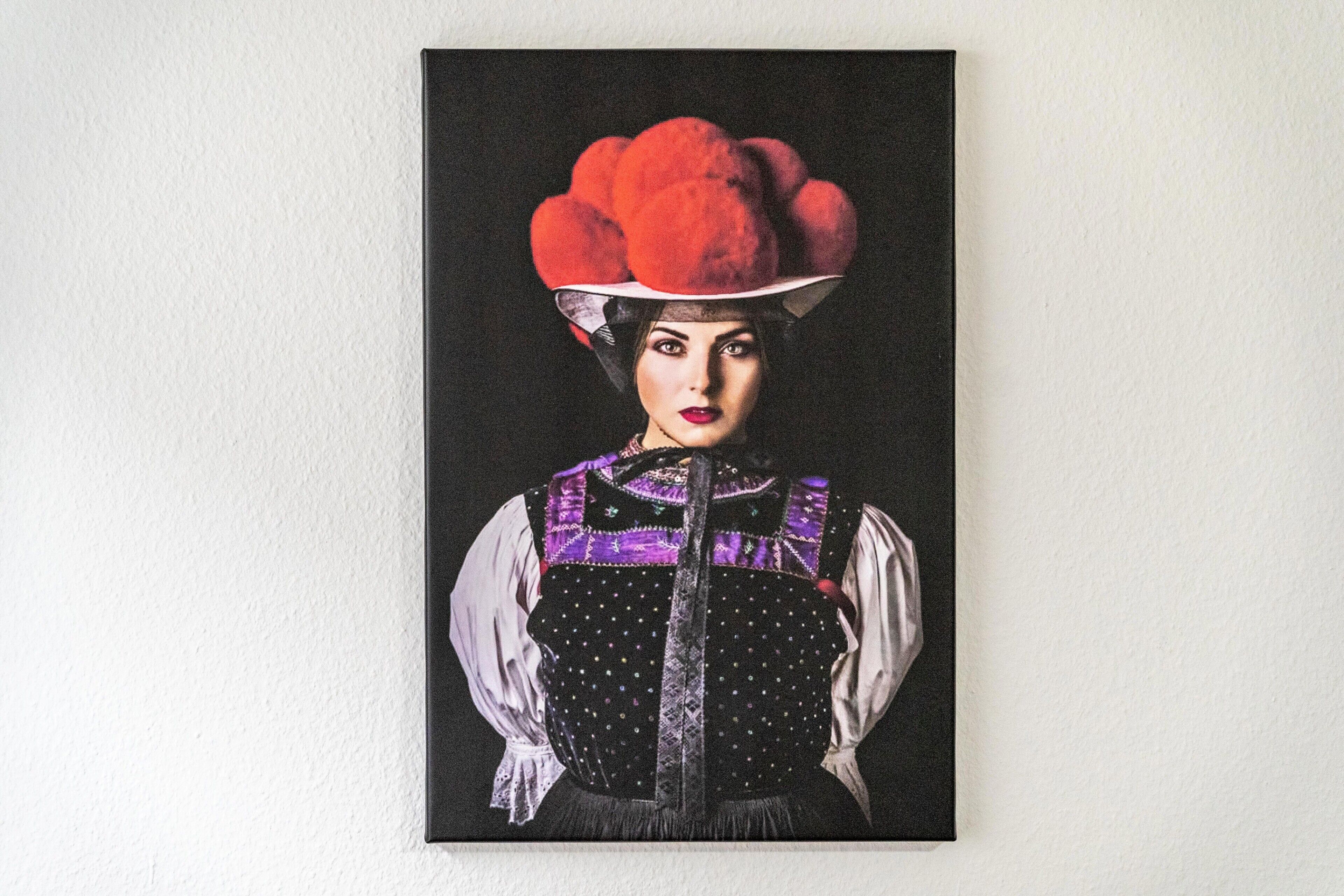 A portrait of a person wearing a distinctive red hat and a patterned vest.