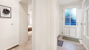 A hallway with a white door, a framed picture on the wall, and a tiled floor. - Apartment 'Moderne Businesswohnung In Toplage' with Wi-Fi (Hannover)