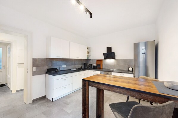Una cocina moderna con armarios blancos, una mesa de madera y un horno empotrado.