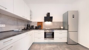 A modern kitchen with white cabinets, a stainless steel oven, a built-in microwave, and a refrigerator. - Apartment 'Moderne Businesswohnung In Toplage' with Wi-Fi (Hannover)