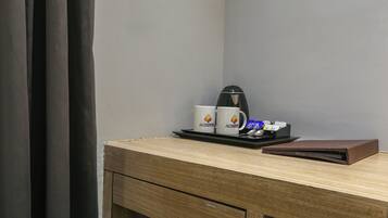 A wooden desk with a coffee maker, two mugs, a tray, and a brown folder.