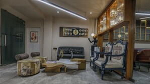 A modern living room with a sofa, armchairs, and a coffee table. There is a painting on the wall and a chandelier. - Aceotel Select Aria - A Luxury Boutique Hotel (Bhopal)