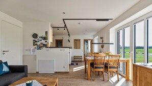 Un espacio habitable moderno con cocina, comedor y ventanas amplias.