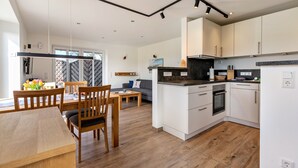 Una cocina moderna con armarios blancos, una mesa de comedor de madera y un sofá en la sala de estar.