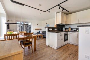 Eine moderne Küche mit weißen Schränken, einem Holzespeisetisch und einem Sofa im Wohnbereich.