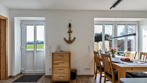 Un comedor con mesa de madera, sillas y vistas amplias a través de grandes ventanales.