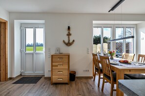 Ein Essbereich mit Holztisch, Stühlen und Blick durch große Fenster.