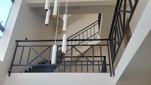 A modern interior with a staircase, black railings, and hanging pendant lights. - Nirvana Club Resort and Spa (Anekal)