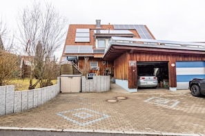 Une maison moderne dotée de panneaux solaires, d’un garage et d’une allée pavée en briques.