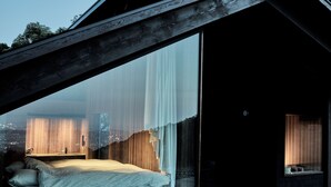 Un dormitorio con un ventanal grande, una cama y vistas de la ciudad.