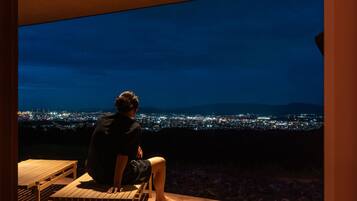 Uma pessoa sentada num banco admirando uma vista noturna da cidade.