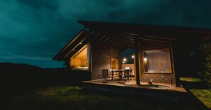 A modern house with a covered patio, a dining area, and a visible kitchen. - Snow Peak YAKEI SUITE ABURAYAMA FUKUOKA (Fukuoka)