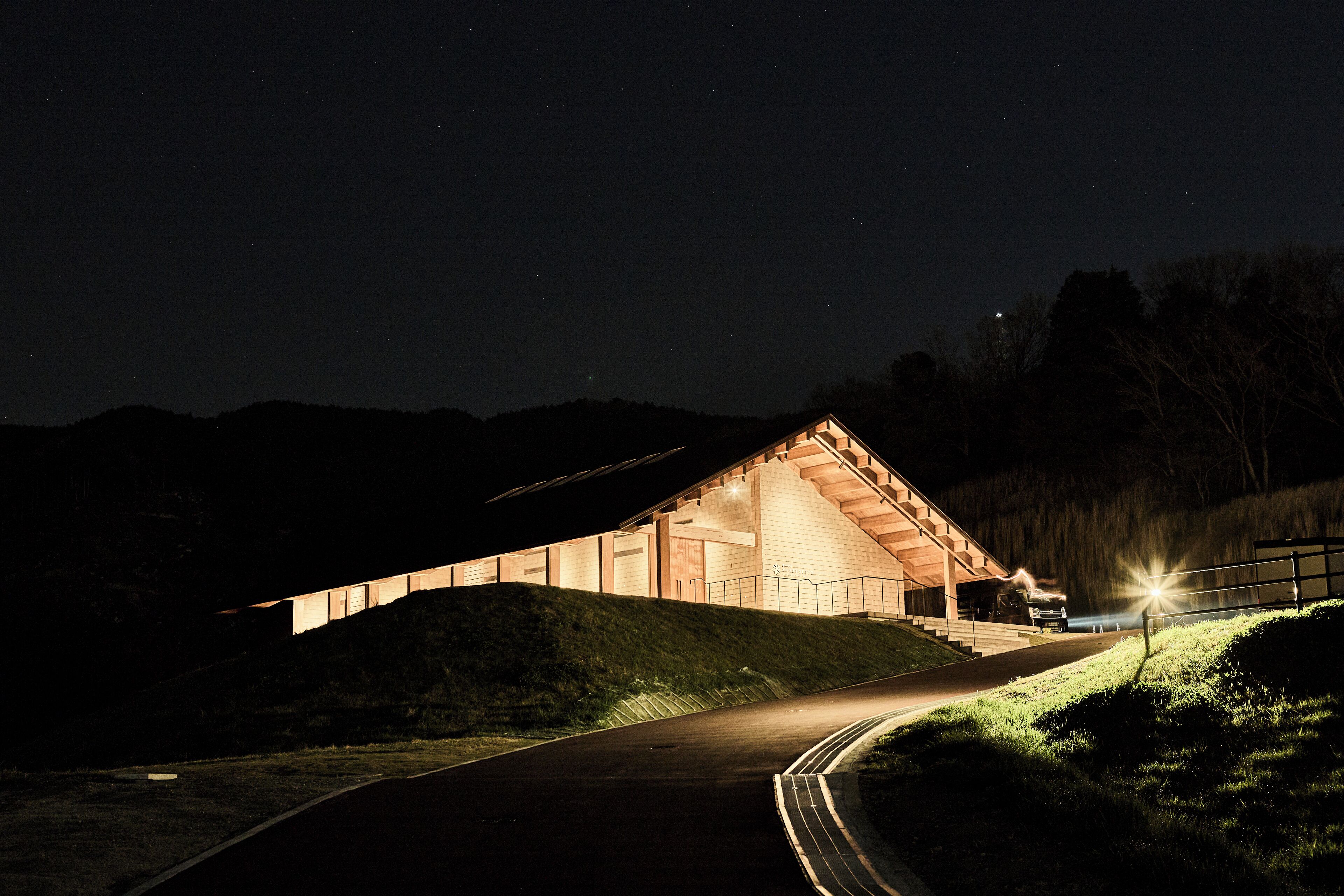 A building with a sloped roof, a staircase leading up to it, and a pathway beside it.